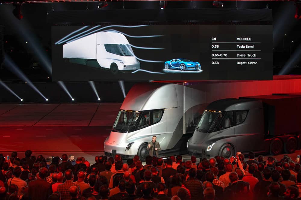 Elon Musk stands in front of two Tesla Semi models during a grand unveiling in 2017.