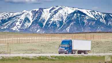 unidentified tractor-trailer on highway with snowy mountains in backdrop