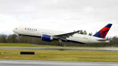 A big white Delta jet with blue tail takes off from runway.