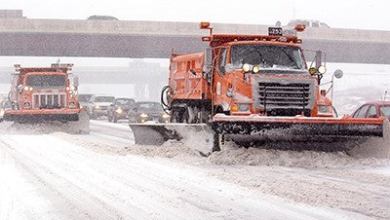 Plow trucks clearing a Minnesota highway, with traffic behind it.