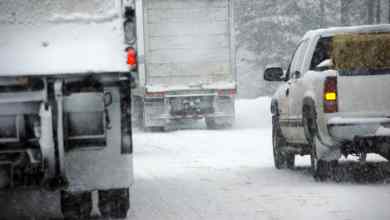 Tractor-trailers heading down a snowy highway.
