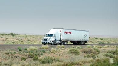 A tractor-trailer of Mullen Group trucking company Payne viewed from the side of a road.