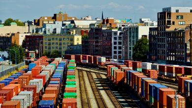 Rail cars loaded with intermodal containers near the port of Vancouver, with the city skyline behind it.