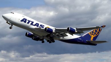 A white Atlas Air jumbo jet taking off against gray sky.