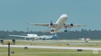 A white plane taking off, approach camera with underside visibile.