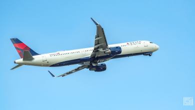 A white and blue-tailed Delta Air Lines jet flying upwards, view from below.