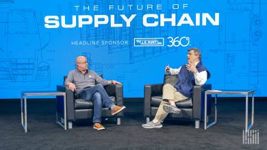 Two men sitting in chairs on a stage and talking to each other.