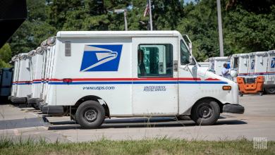 Rows of Postal Service vans in a parking lot.