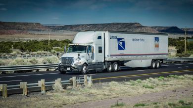 An 18-wheel Postal Service truck moves down the highway.