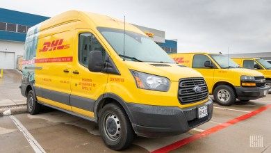 Yellow DHL delivery vans in a parking lot.