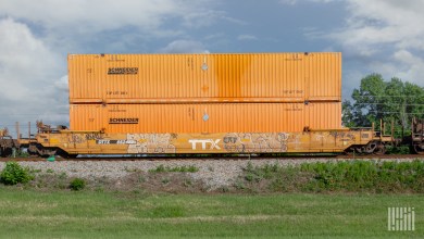 Two orange Schneider intermodal containers doubled stacked on a well car