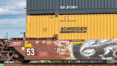 An orange Schneider intermodal container on a well car