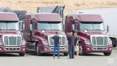 truck drivers talking in front of trucks at a truck stop