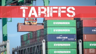 Container ship unloading with tariff banner.