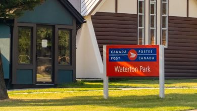 A suburan Canada Post office with red-and-blue sign on the lawn.