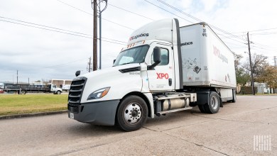 An XPO daycab leaving a facility with trailers
