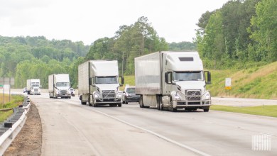 tractor-trailers traveling up a hill on a highway