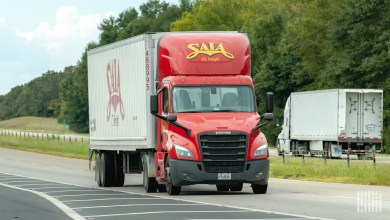 A red Saia daycab pulling a trailer on a highway