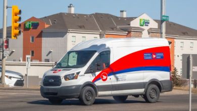 A red-white Canada Post van on a city street.