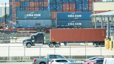 a blue sleeper cab leaving a port gate pulling and ocean container