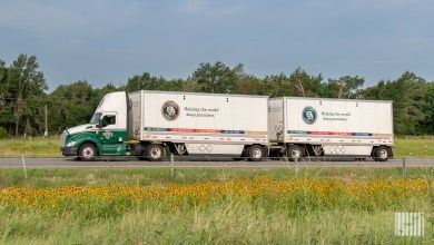 An Old Dominion tractor pulling two pup trailers on a side road