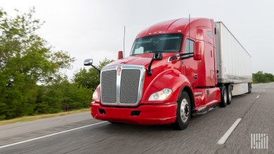 a red tractor pulling a trailer on a highway