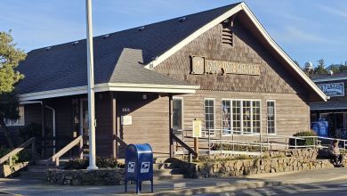 A rural post office in Cannon Beach, Oregon, seen from the front with a post box in front.