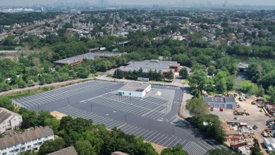 Aerial view of Outpost’s truck terminal in Clifton, New Jersey, featuring a large paved parking area, warehouse buildings, and the New York City skyline in the background.