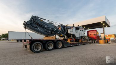 Heavy-haul flatbed with oversized Wirtgen milling machine at truck stop, representing open-deck freight now priced by Truckstop Heavy Haul Rates.