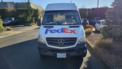 Front view of a FedEx delivery van in a parking lot.