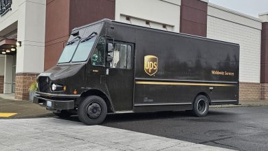 Side view of a UPS van parked next to suburban retail store.