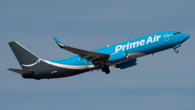 A two-tone blue Amazon Prime jet in flight as seen from below.