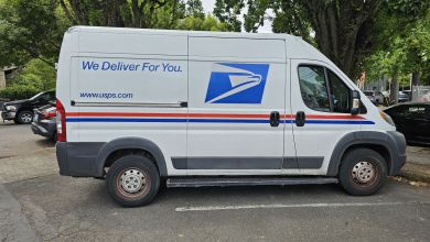 Side view of a USPS delivery van in a parking spot.