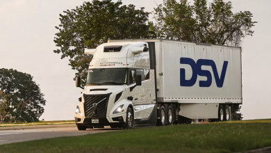 White Volvo VNL Autonomous semi-truck with large blue DSV logo on the trailer driving on a highway during the launch of autonomous freight operations between Dallas and Houston