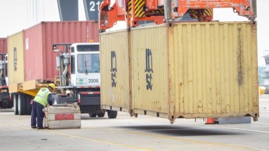containers being loaded on yard trucks at port