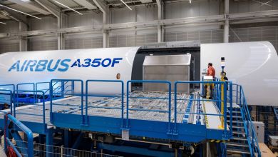 Fuselage of an A350 freighter aircraft in the manufacturing hall as technicians install a cargo door.