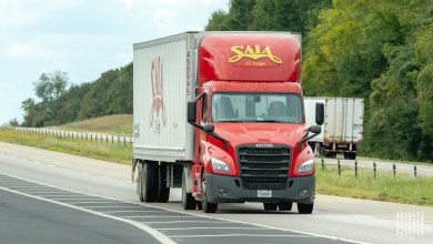 A red Saia daycab pulling a Saia trailer on a highway