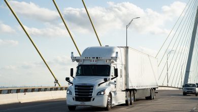Bot Auto autonomous Freightliner truck with roof-mounted sensors driving across a bridge on a sunny day