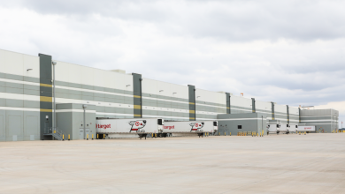 Backside of a large warehouse with Target-brand trailers backed to loading docks in the distance.