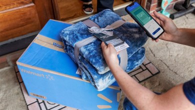 A blue Walmart box delivered to a residential doorstep with the driver scanning a bar code to document the delivery.