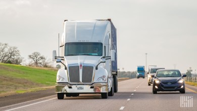 a white sleeper cab pulling a blue ocean container