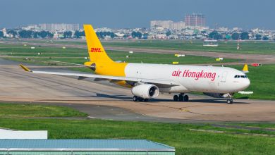 A yellow-tailed Air Hong Kong Express with DHL markings lines up for departure from an airport.