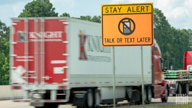 A Knight Transportation trailer on a highway with a no texting sign in the forefront