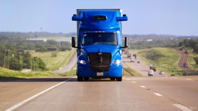 Aurora second-generation driverless Class 8 truck, a blue International LT tractor with roof-mounted sensors, traveling on a multi-lane highway