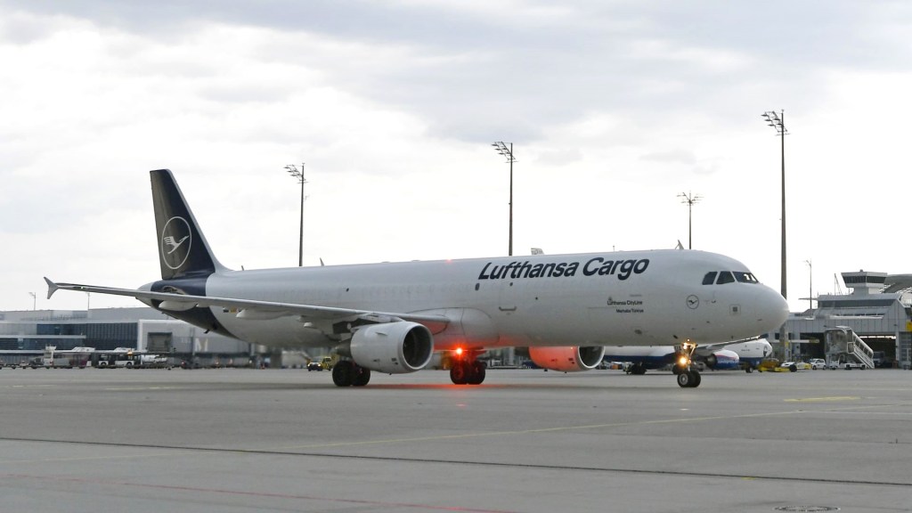 A blue-tailed Lufthansa Cargo jet moves on an airport taxiway.